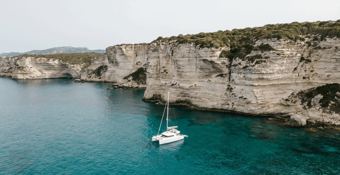 Catamaran au mouillage devant les falaises calcaires de Bonifacio en Corse